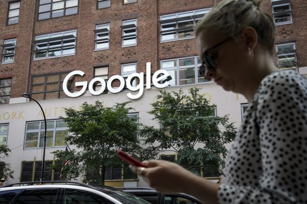 Một người phụ nữ nhìn vào điện thoại thông minh của mình khi đi ngang qua tòa nhà Google ở New York hôm 03/06/2019. (Ảnh: Drew Angerer/Getty Images)