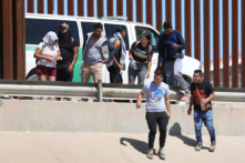 Công dân Venezuela đi dọc hàng rào biên giới tới chỗ một chiếc xe tải của Lực lượng Tuần tra Biên giới đang đợi sau khi vượt sông Rio Grande trái phép từ Mexico, ở El Paso, Texas, hôm 21/09/2022. (Ảnh: Joe Raedle/Getty Images)