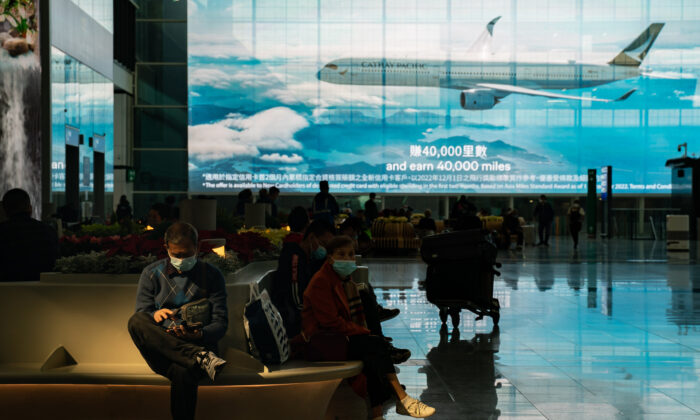 Du khách ngồi tại sảnh đến của Phi trường Quốc tế Hồng Kông ở Hồng Kông hôm 30/12/2022. (Ảnh: Anthony Kwan/Getty Images)