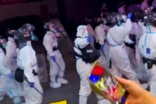 Cảnh sát chống bạo động trong các bộ đồ bảo hộ cá nhân đi bộ xuống một con đường khi các cuộc biểu tình phản đối các hạn chế về COVID-19 diễn ra ở Quảng Châu, một thành phố thuộc tỉnh Quảng Đông, Trung Quốc. Ảnh chụp màn hình này được trích từ một video trên mạng xã hội đăng tải hôm 29/11/2022. (Ảnh: Video do Reuters thu thập được/Thông qua Reuters)