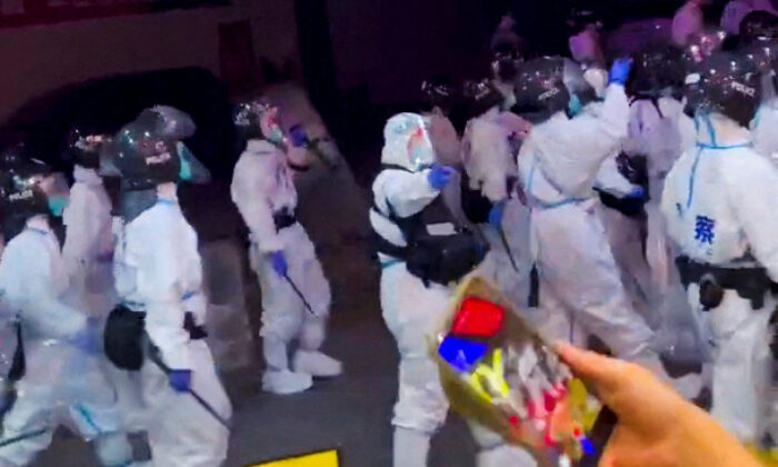 Cảnh sát chống bạo động trong các bộ đồ bảo hộ cá nhân đi bộ xuống một con đường khi các cuộc biểu tình phản đối các hạn chế về COVID-19 diễn ra ở Quảng Châu, một thành phố thuộc tỉnh Quảng Đông, Trung Quốc. Ảnh chụp màn hình này được trích từ một video trên mạng xã hội đăng tải hôm 29/11/2022. (Ảnh: Video do Reuters thu thập được/Thông qua Reuters)