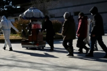 Các thành viên trong gia đình đi theo sau một phương tiện đang di chuyển bình đựng tro cốt của người thân tại một lò hỏa táng ở Bắc Kinh hôm 22/12/2022. (Ảnh: STF/AFP qua Getty Images)