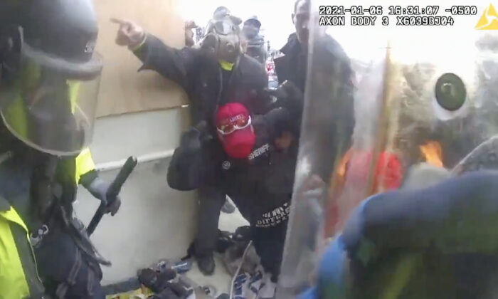 Một người biểu tình giúp đỡ cựu phó cảnh sát trưởng Ronald McAbee sau khi ông cố gắng thực hiện hô hấp nhân tạo cho cô Rosanne Boyland đang bị bất tỉnh tại Điện Capitol Hoa Kỳ. Đoạn phim bằng máy quay gắn trên người (bodycam) mới cung cấp một góc nhìn mới về những nỗ lực để cứu sống cô Boyland, 34 tuổi, người đã qua đời vào ngày 06/01/2021. (Ảnh: Sở Cảnh sát Thủ đô/Ảnh chụp màn hình qua The Epoch Times)