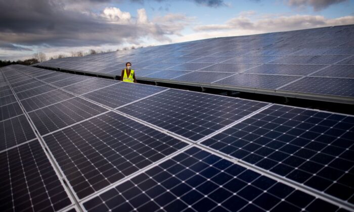 Một người phụ nữ đi qua các tấm quang năng của nhà máy quang điện do Generale du Soleil (GDS) lắp đặt và Energ’iV SEML vận hành tại một nơi vốn đã từng là bãi rác thải, vào ngày 08/12/2020 ở Guignen, miền tây nước Pháp. (Ảnh: Loic Venance/AFP qua Getty Images)