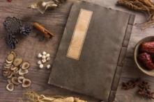 Nhiều loại dược liệu Trung Quốc và một quyển sách Đông y. (Ảnh: Shutterstock)