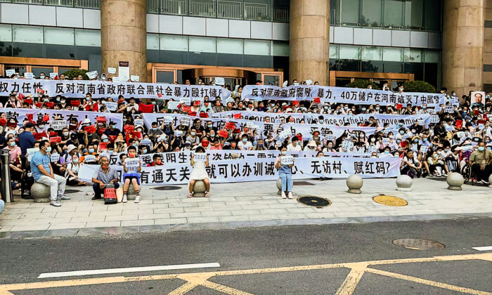 Người dân cầm biểu ngữ và hô vang khẩu hiệu trong một cuộc biểu tình ở lối vào một chi nhánh của ngân hàng trung ương Trung Quốc tại Trịnh Châu, tỉnh Hà Nam, miền trung Trung Quốc, hôm 10/07/2022. (Ảnh: Yang/AP Photo)