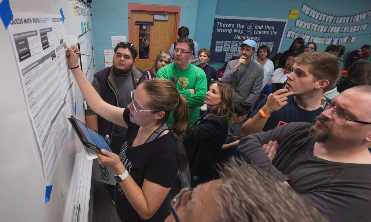 Các cử tri nhìn một tình nguyện viên kiểm phiếu trong cuộc họp bầu ở tiểu bang Nevada để đề cử ứng cử viên tổng thống của Đảng Dân Chủ tại điểm bỏ phiếu bên trong trường trung học Coronado ở Las Vegas, tiểu bang Nevada, vào ngày 22/02/2020. (Ảnh: Mark Ralston/AFP qua Getty Images)