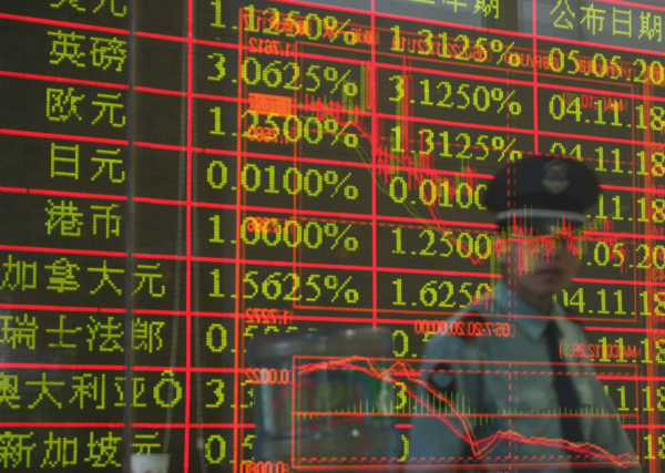 Một nhân viên bảo vệ và một bảng điện tử hiển thị lãi suất tiền gửi ngoại tệ được phản chiếu trên một bức tường kính của một ngân hàng ở Thành Đô, tỉnh Tứ Xuyên, Trung Quốc, vào ngày 22/07/2005. (Ảnh: Trung Quốc/Getty Images)