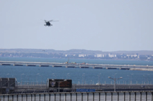 Một trực thăng quân sự của Nga bay qua các phần bị hư hỏng của một đoạn đường dành cho xe hơi trên Cầu Crimea nối đất liền của Nga và bán đảo Crimea qua Eo biển Kerch không xa Kerch, Crimea, hôm 17/07/2023. (Ảnh: AP Photo)