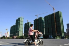 Một người phụ nữ đi xe máy ngang qua công trường xây dựng khu nhà ở của Tập đoàn Hằng Đại (Evergrande) ở Trú Mã Điếm, tỉnh Hà Nam, miền trung Trung Quốc hôm 14/09/2021. (Ảnh: Jade Gao/AFP qua Getty Images)