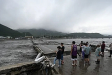 Một số người đang đứng xem một cây cầu bị sập trên sông Đại Thạch Hà sau các cơn mưa lớn ở quận Phòng Sơn, thành phố Bắc Kinh hôm 01/08/2023. Hôm 01/08, truyền thông nhà nước cho biết đã có ít nhất 11 người thiệt mạng và 13 người mất tích sau trận mưa lớn tấn công Bắc Kinh, trong những trận mưa như trút nước khiến đường xá ngập nước và những khu phố ngập trong bùn. (Ảnh: Pedro PARDO/AFP qua Getty Images)