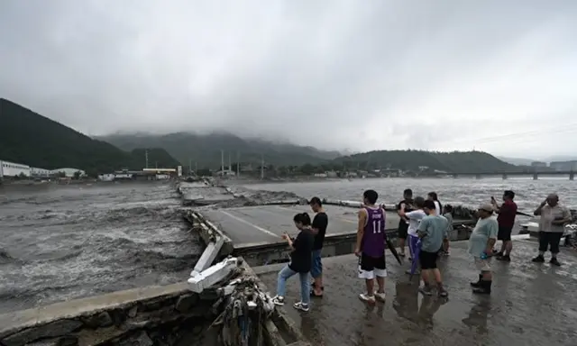 Một số người đang đứng xem một cây cầu bị sập trên sông Đại Thạch Hà sau các cơn mưa lớn ở quận Phòng Sơn, thành phố Bắc Kinh hôm 01/08/2023. Hôm 01/08, truyền thông nhà nước cho biết đã có ít nhất 11 người thiệt mạng và 13 người mất tích sau trận mưa lớn tấn công Bắc Kinh, trong những trận mưa như trút nước khiến đường xá ngập nước và những khu phố ngập trong bùn. (Ảnh: Pedro PARDO/AFP qua Getty Images)