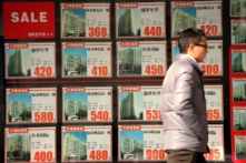 Một người đàn ông đi trước cửa sổ của một đại lý địa ốc ở Thượng Hải, vào 04/12/2012. (Ảnh: Peter Parks/AFP qua Getty Images)