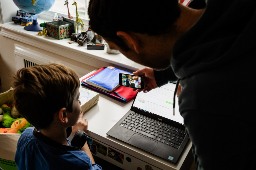 Em Joachim (trái), một học sinh không đến trường trong thời gian diễn ra đại dịch do trường học đóng cửa, ghi âm tin nhắn thoại trên chiếc điện thoại của cha mình và gửi cho các bạn cùng lớp như một phần bài tập về nhà của em ở Hoa Thịnh Đốn vào ngày 20/03/2020. (Ảnh: Eric Baradat/AFP qua Getty Images)