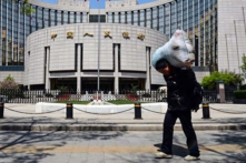 Một công nhân di cư ở Trung Quốc đi ngang qua Ngân hàng Nhân dân Trung Quốc ở Bắc Kinh hôm 01/05/2013. (Ảnh: Mark Ralston/AFP qua Getty Images)