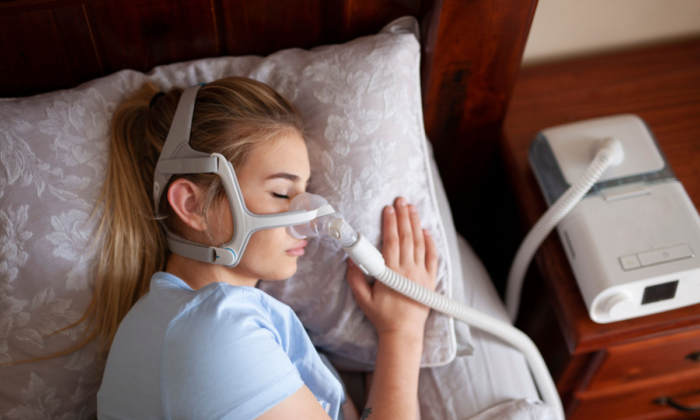 Một cô gái trẻ đeo máy CPAP khi ngủ để điều trị chứng ngưng thở khi ngủ. (Ảnh: Independence_Project/Shutterstock)