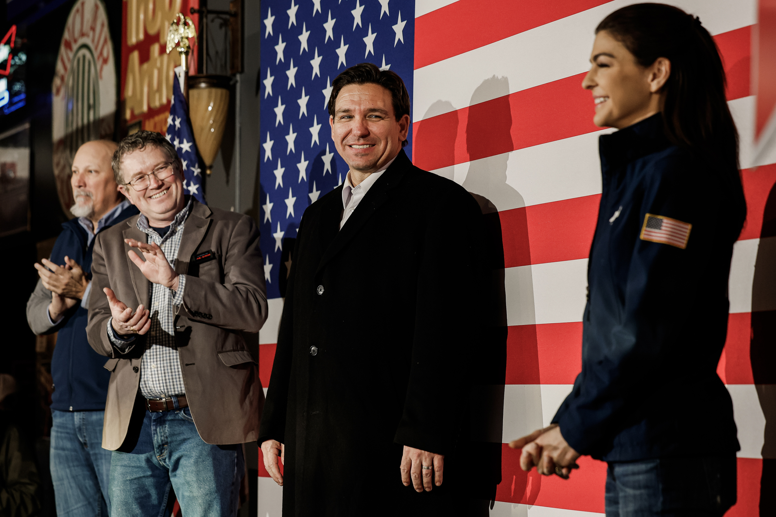 Ứng cử viên tổng thống của Đảng Cộng Hòa — Thống đốc tiểu bang Florida Ron DeSantis (giữa) — mỉm cười với phu nhân của mình, bà Casey DeSantis (phải), khi bà được Dân biểu Chip Roy (Cộng Hòa-Texas) (trái), và Dân biểu Thomas Massie (Cộng Hòa-Kentucky) (thứ hai từ trái qua) vỗ tay tán thưởng trong một sự kiện vận động tranh cử tại Chrome Horse Saloon một ngày trước cuộc họp bầu Iowa ở Cedar Rapids, Iowa, hôm 14/01/2024. (Ảnh: Chip Somodevilla/Getty Images)