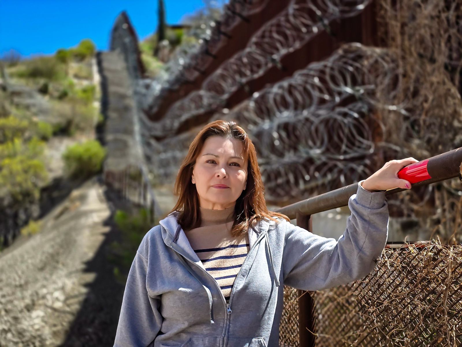 Bà Anna Pareda, một nhân viên Quan thuế và Bảo vệ Biên giới đã về hưu, đứng trước bức tường biên giới ở Nogales, Arizona, hôm 23/03/2024. (Ảnh: Allan Stein/The Epoch Times)