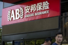 Khách bộ hành đi ngang qua lối vào một văn phòng của Tập đoàn Bảo hiểm An Bang (Anbang Insurance Group) ở Bắc Kinh, hôm 14/06. (Ảnh: Mark Schiefelbein/AP Photo)