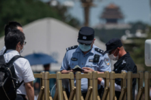 Công an (phải) kiểm tra sổ thông hành của một người ngoại quốc (trái) tại cổng an ninh ở lối vào Quảng trường Thiên An Môn tại Bắc Kinh vào ngày 04/06/2020. (Ảnh: NICOLAS ASFOURI/AFP qua Getty Images)