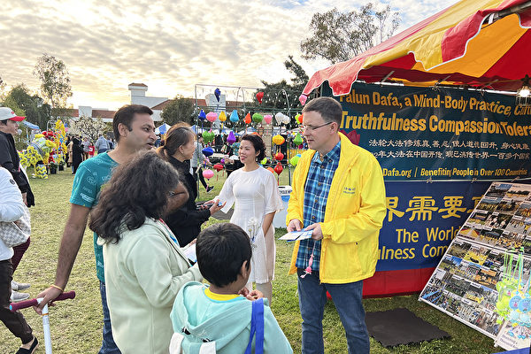 Anh Mike Tuck (người mặc áo khoác vàng) đang giới thiệu Pháp Luân Đại Pháp cho du khách tại công viên. (Ảnh: Được đăng dưới sự cho phép của anh Mike)