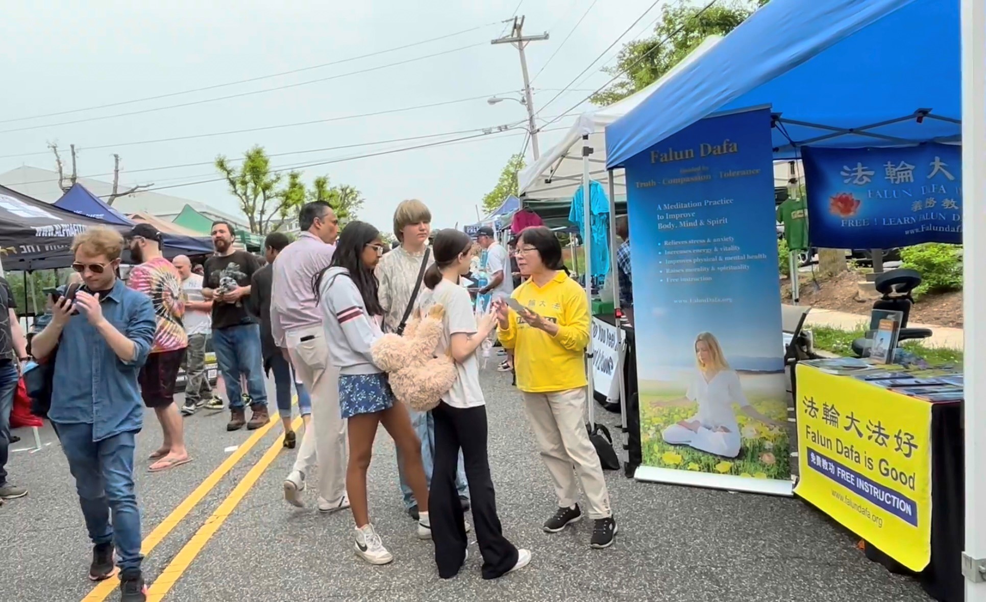 Một nhóm thanh niên thích thú lắng nghe học viên Pháp Luân Công giới thiệu về Pháp Luân Đại Pháp. (Ảnh: Tịnh Kỳ/The Epoch Times)