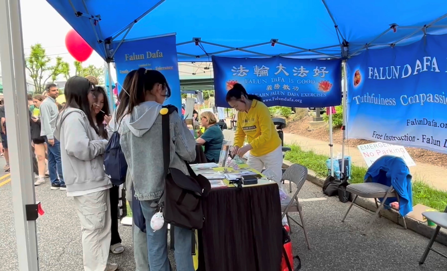 Một nhóm các thiếu nữ xin các học viên Pháp Luân Công những bông hoa sen nhỏ tượng trưng cho may mắn. (Ảnh: Tịnh Kỳ/The Epoch Times)