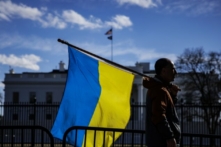 Một người đàn ông mang theo cờ Ukraine đứng trên Đại lộ Pennsylvania trước Tòa Bạch Ốc khi những người biểu tình tụ tập để phản đối cuộc xâm lược của Nga ở Thủ đô Hoa Thịnh Đốn, vào ngày 25/02/2022 (Ảnh: Samuel Corum/Getty Images)
