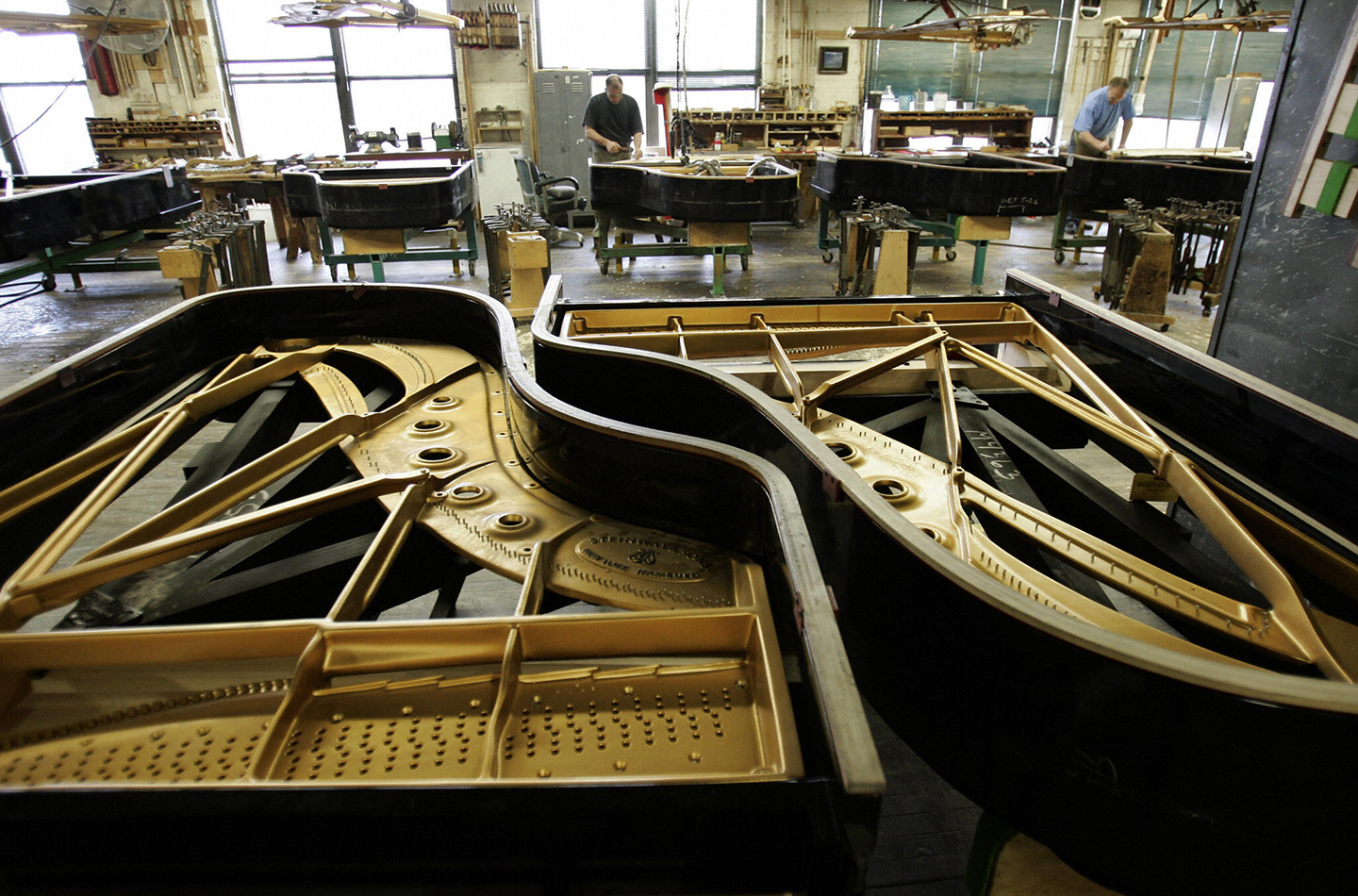 Các kỹ thuật viên tại nhà máy Steinway & Sons ở Thành phố Long Island, New York, đặt bảng cộng hưởng vào những chiếc đại dương cầm. (Ảnh: Timothy A. Clary/Getty Images)