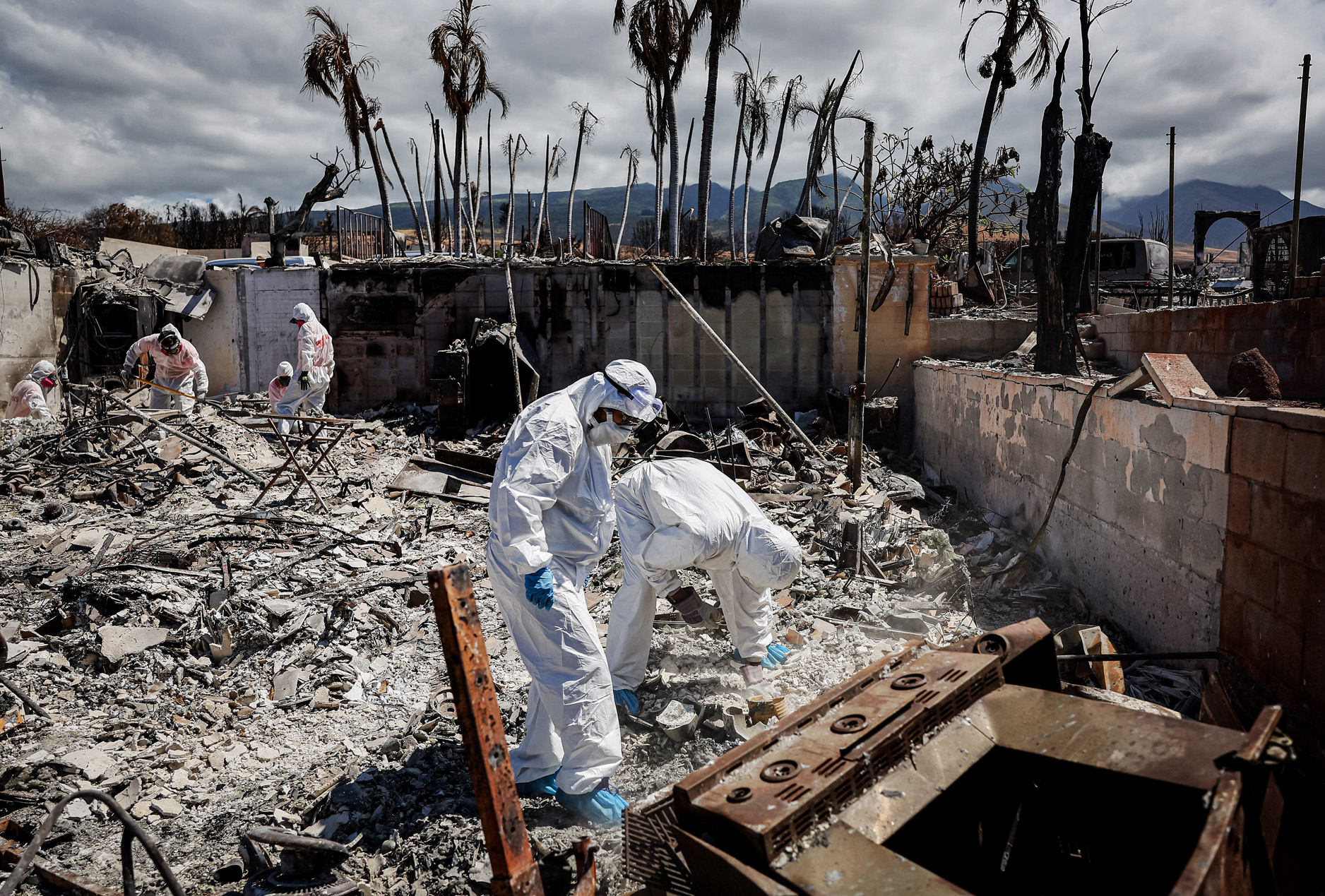 (Ảnh trên bên trái) Ông William Anthony nghỉ ngơi sau khi tìm kiếm các vật dụng cá nhân tại ngôi nhà đã bị tàn phá của mình ở Lahaina, Hawaii, vào ngày 05/10/2023. (Ảnh trên bên phải) Cô Lori Brodeur nhìn lại những món đồ trang sức được tình nguyện viên của Samaritan’s Purse tìm thấy. Các tình nguyện viên đã tìm kiếm đồ đạc từ đống tro tàn trong ngôi nhà của cô ở Lahaina, Hawaii, vào ngày 05/10/2023. (Ảnh dưới) Cô Caroline và anh William Anthony (bên phải) tìm kiếm các vật dụng cá nhân trong đống đổ nát ở ngôi nhà của họ, trong khi các tình nguyện viên của Samaritan’s Purse (bên trái) cùng giúp họ, ở Lahaina, Hawaii, vào ngày 05/10/2023. (Ảnh: Mario Tama/Getty Images)