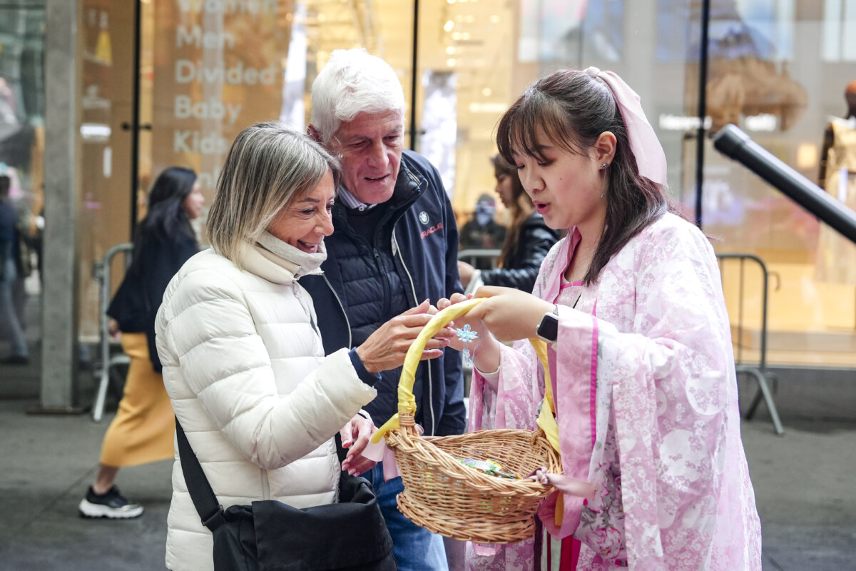 Một học viên Pháp Luân Công tặng hoa sen ‘chân, thiện, nhẫn’ cho khách bộ hành tại cuộc diễn hành kỷ niệm Ngày Pháp Luân Đại Pháp Thế giới, tại thành phố New York, hôm 10/05/2024. (Ảnh: Samira Bouaou/The Epoch Times)