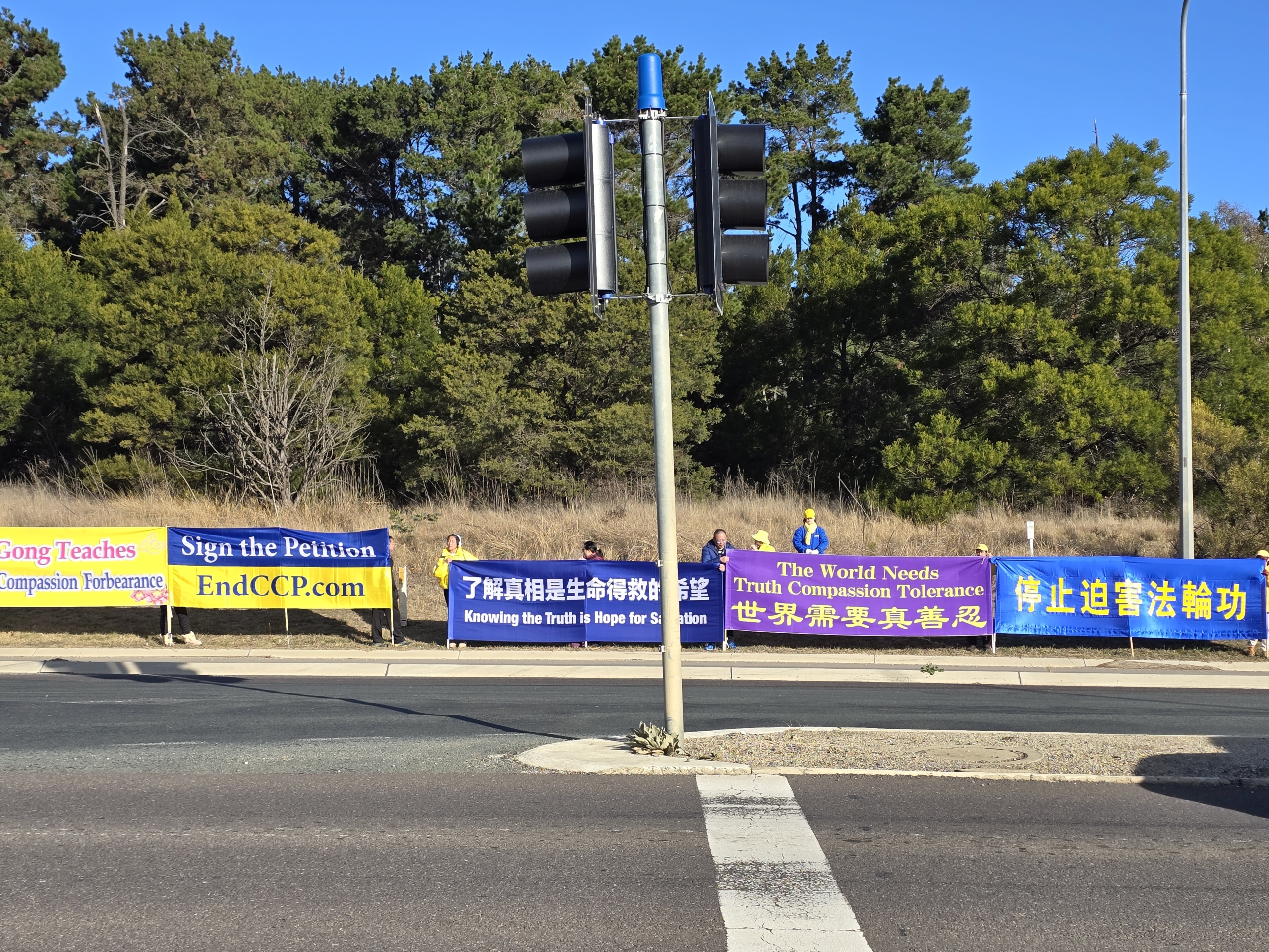 Các học viên Pháp Luân Công giương biểu ngữ trên đường từ phi trường Canberra đến khách sạn của ông Lý Cường để biểu đạt nguyện vọng của mình. (Ảnh: Lạc Á/The Epoch Times)