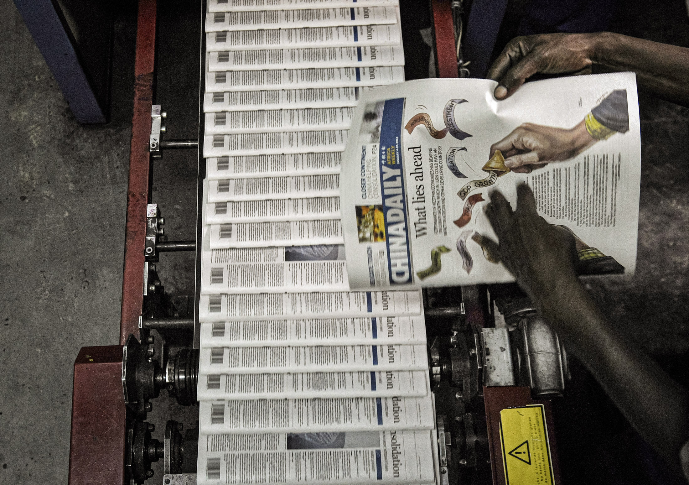 Một kỹ thuật viên đang xem xét các tờ báo China Daily do Trung Quốc sở hữu tại nhà in ở Nairobi, Kenya, hồi tháng 12/2013. (Ảnh: Tony Karumba/AFP via Getty Images)