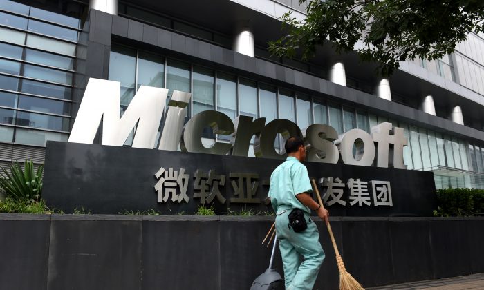 Nhân viên dọn dẹp vệ sinh đi ngang qua biển hiệu Microsoft bên ngoài một tòa nhà văn phòng Microsoft ở Bắc Kinh, vào ngày 31/07/2014. (Ảnh: Greg Baker/AFP/Getty Images)