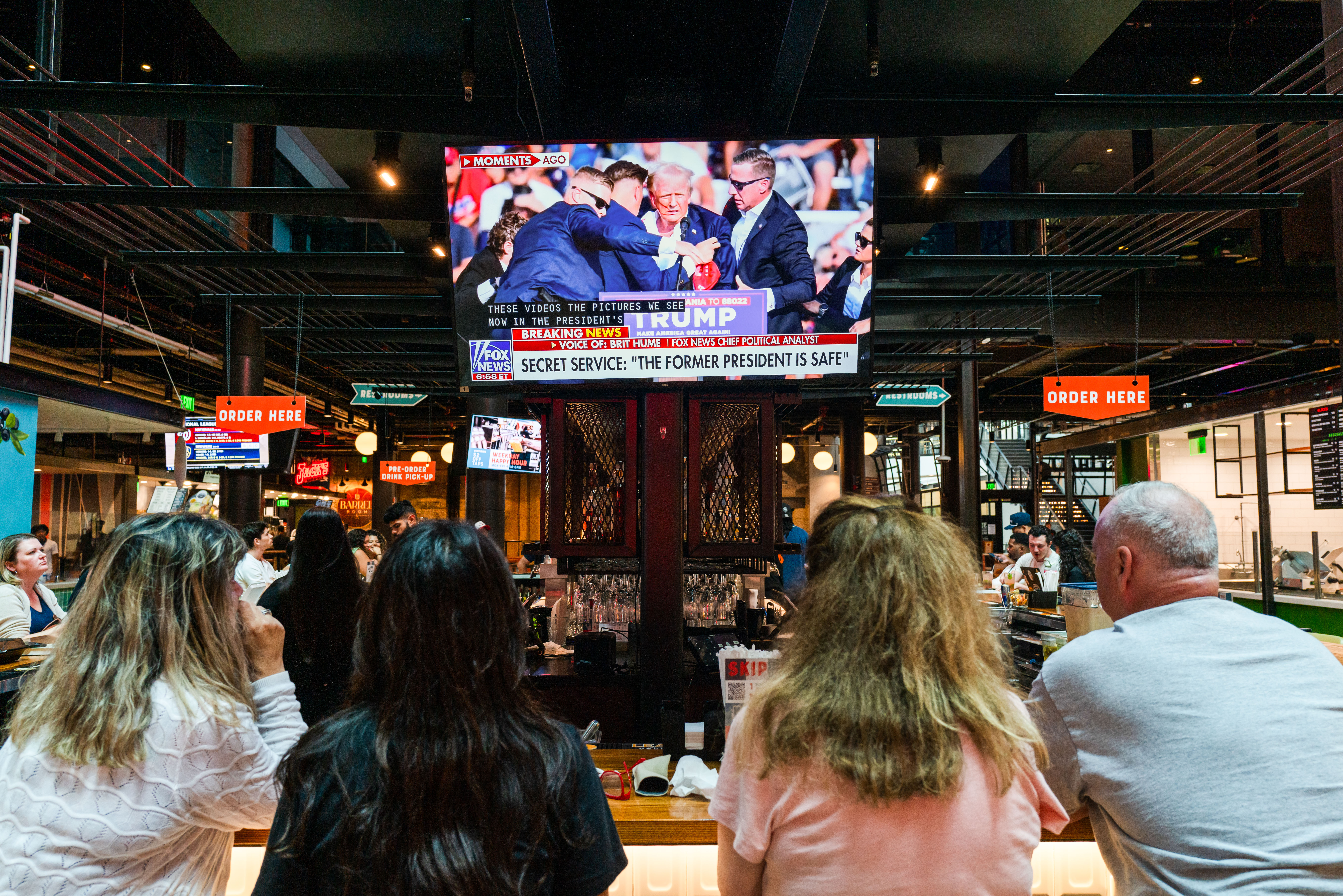 Người dân theo dõi vụ nổ súng được phát sóng trên truyền hình tại một quán rượu ở Milwaukee, Wisconsin, hôm 13/07/2024. (Ảnh: Spencer Platt/Getty Images)