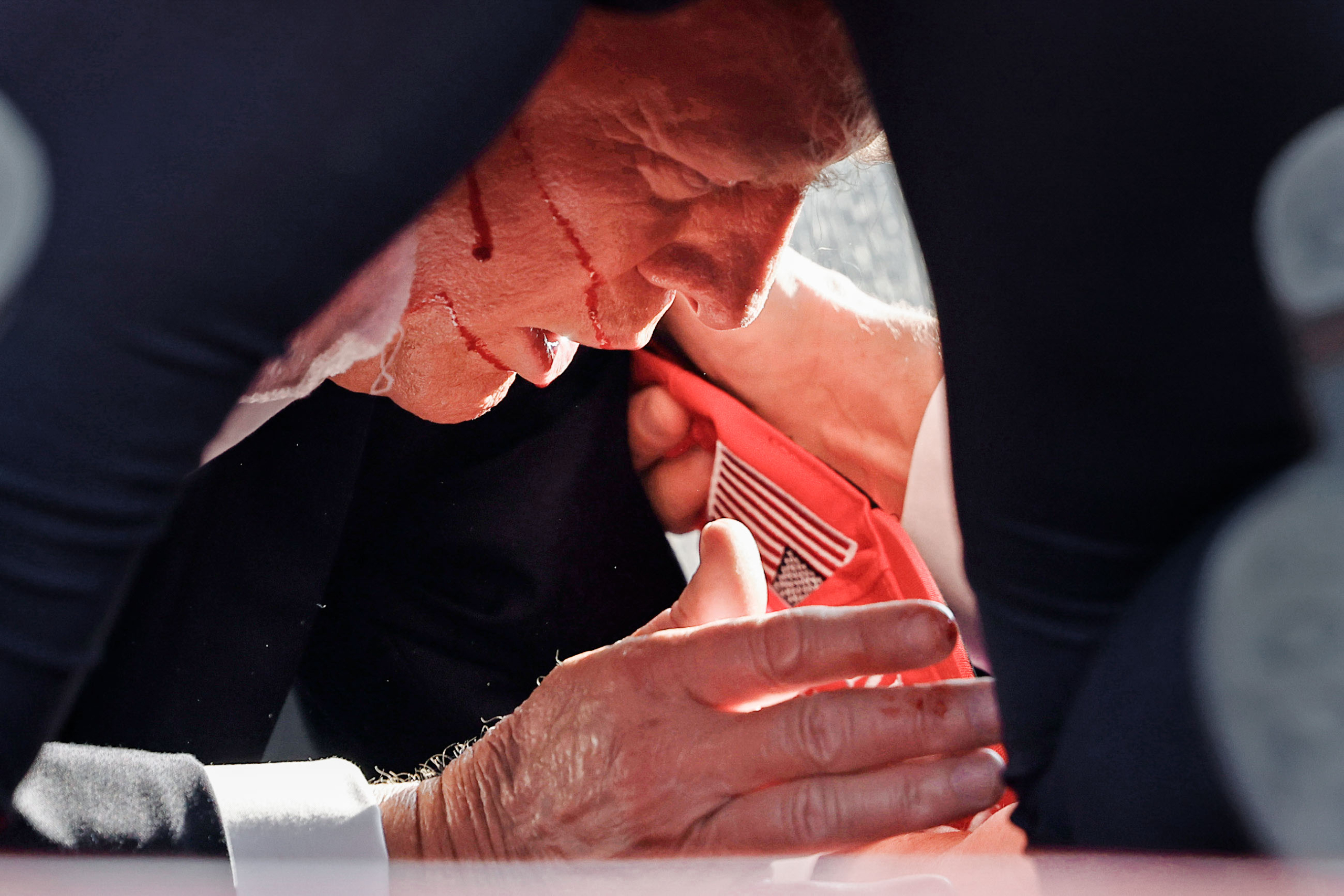 Nhân viên Sở Mật vụ chăm sóc cho cựu Tổng thống Donald Trump trên sân khấu sau khi ông bị đạn bắn sượt qua. (Ảnh: Anna Moneymaker/Getty Images)