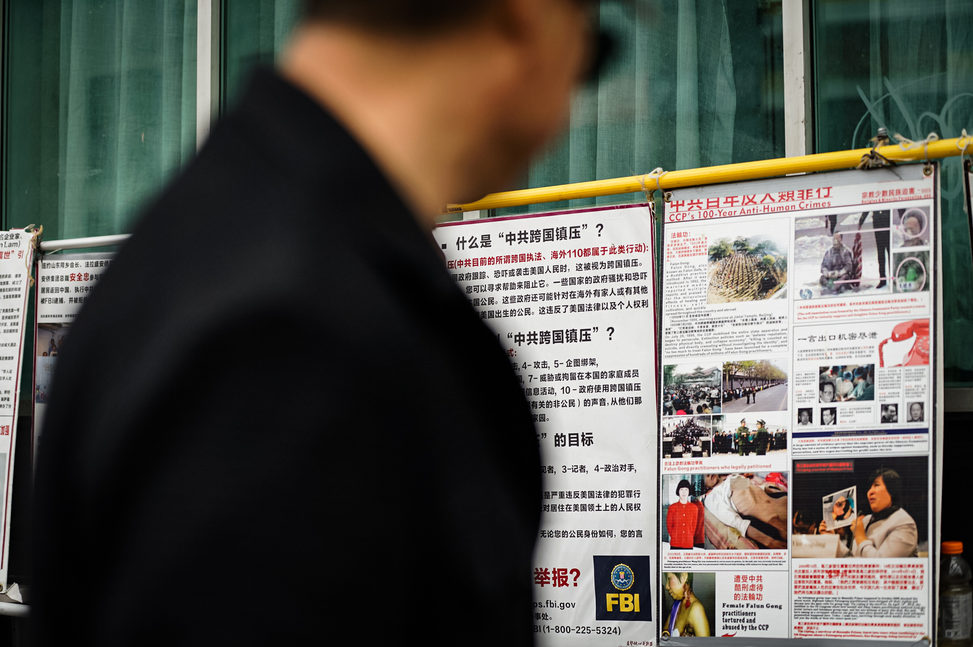 Người qua đường đọc bảng phơi bày thông tin tại một quầy thông tin Pháp Luân Công ở Flushing, khu Queens, thành phố New York, hôm 21/04/2024. (Ảnh: Chung I Ho/The Epoch Times)