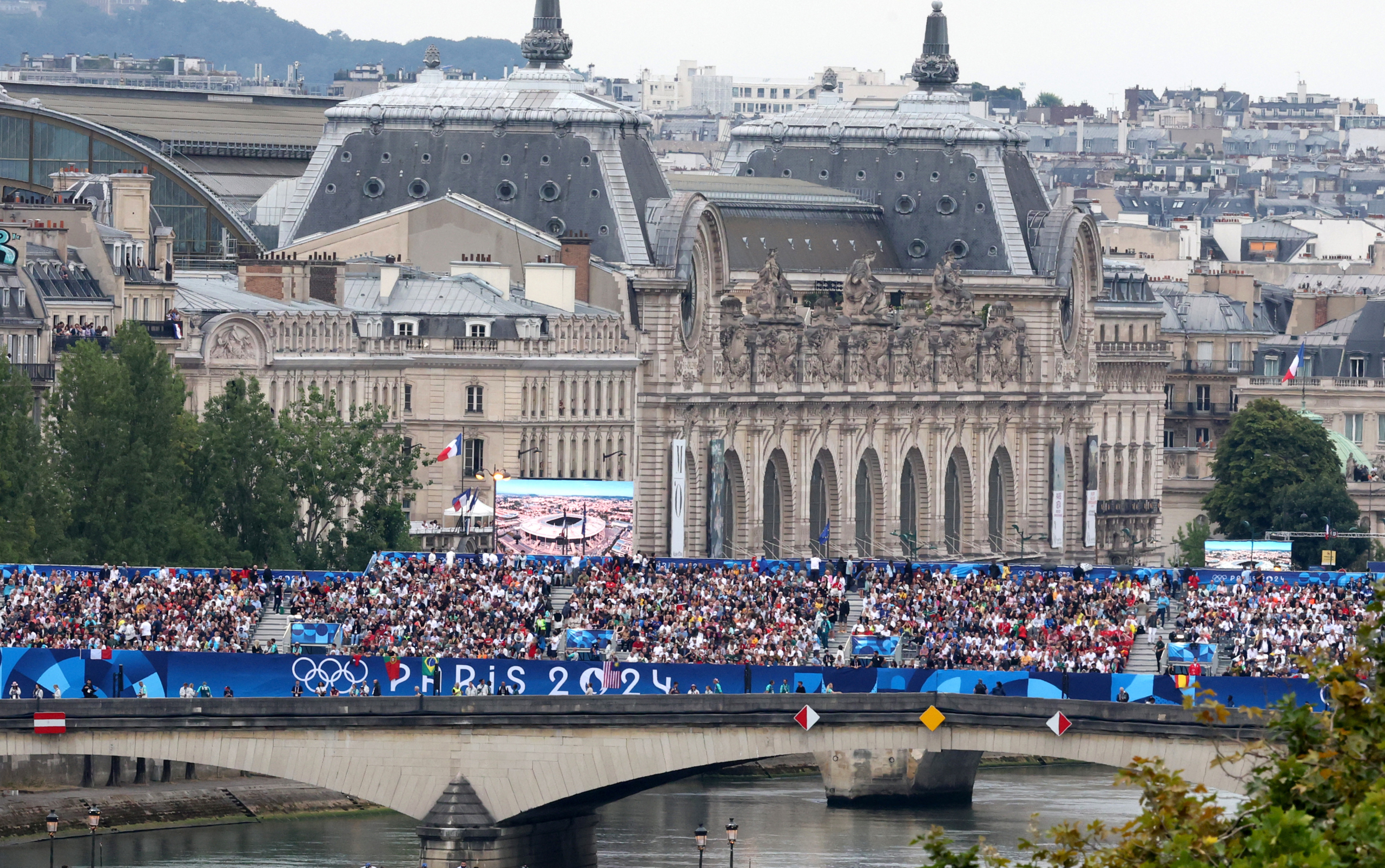 Khán giả trên cây cầu bắc qua sông Seine trong lễ khai mạc Thế vận hội Paris 2024 tại Paris, hôm 26/07/2024. (Ảnh: Zhang Yuwei-Pool/Getty Images)